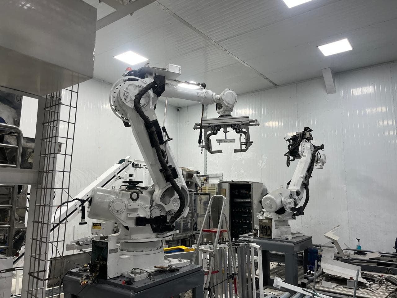 Dois robôs industriais instalados em uma célula de automação.